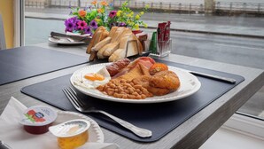 A breakfast plate with toast, beans, eggs, and sausages on a table with a view of the sea. - Hotel Santa Maria (Blackpool)