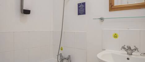 A bathroom with a bathtub, a sink, a showerhead, and a mirror.