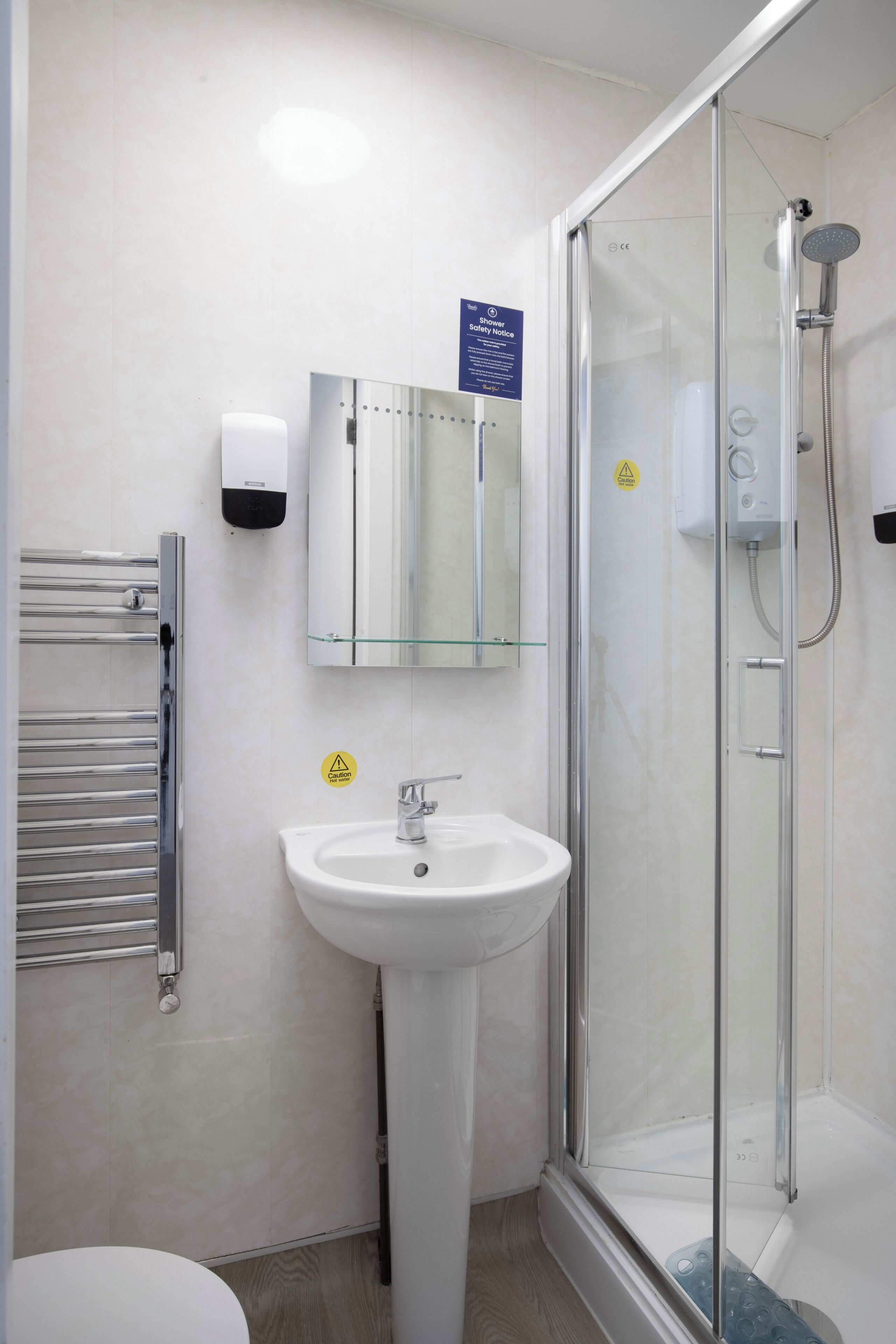 Een badkamer met een douchecabine van glas, een wastafel en een handdoekhouder.