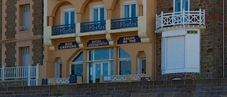 Um hotel com vários andares, varandas, café e entrada visível.
