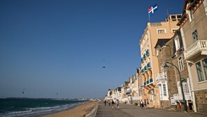 Um calçadão à beira-mar com edifícios, uma bandeira e céu claro.
