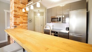 A kitchen with a wooden countertop, stainless steel appliances, and a brick accent wall.