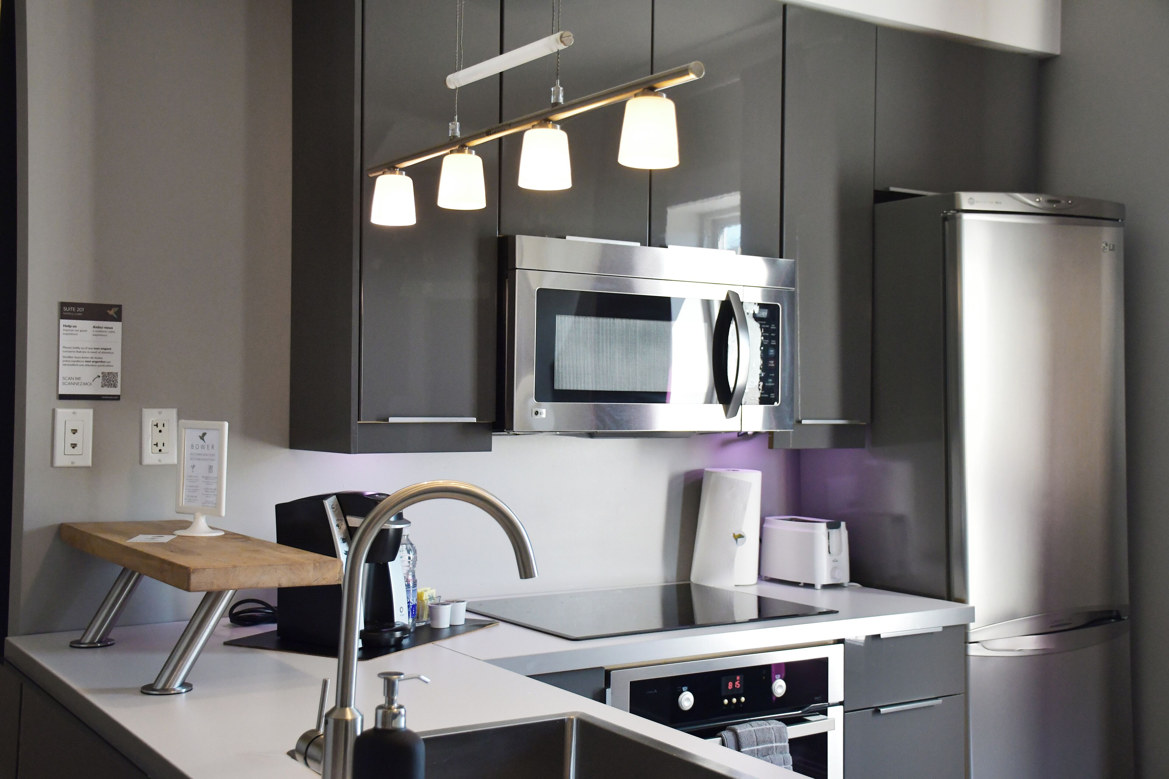 Una cocina moderna con electrodomésticos de acero inoxidable, una encimera de madera e iluminación colgante.