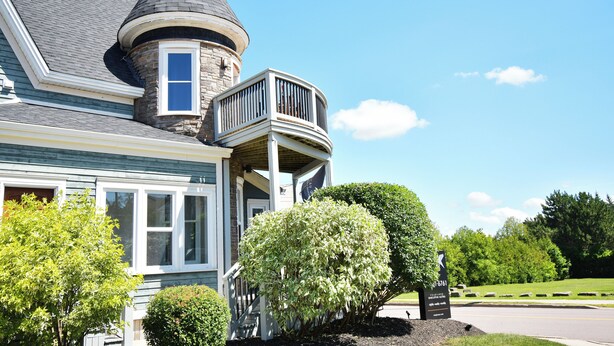 A house with a turret, a balcony, and a well-maintained lawn.