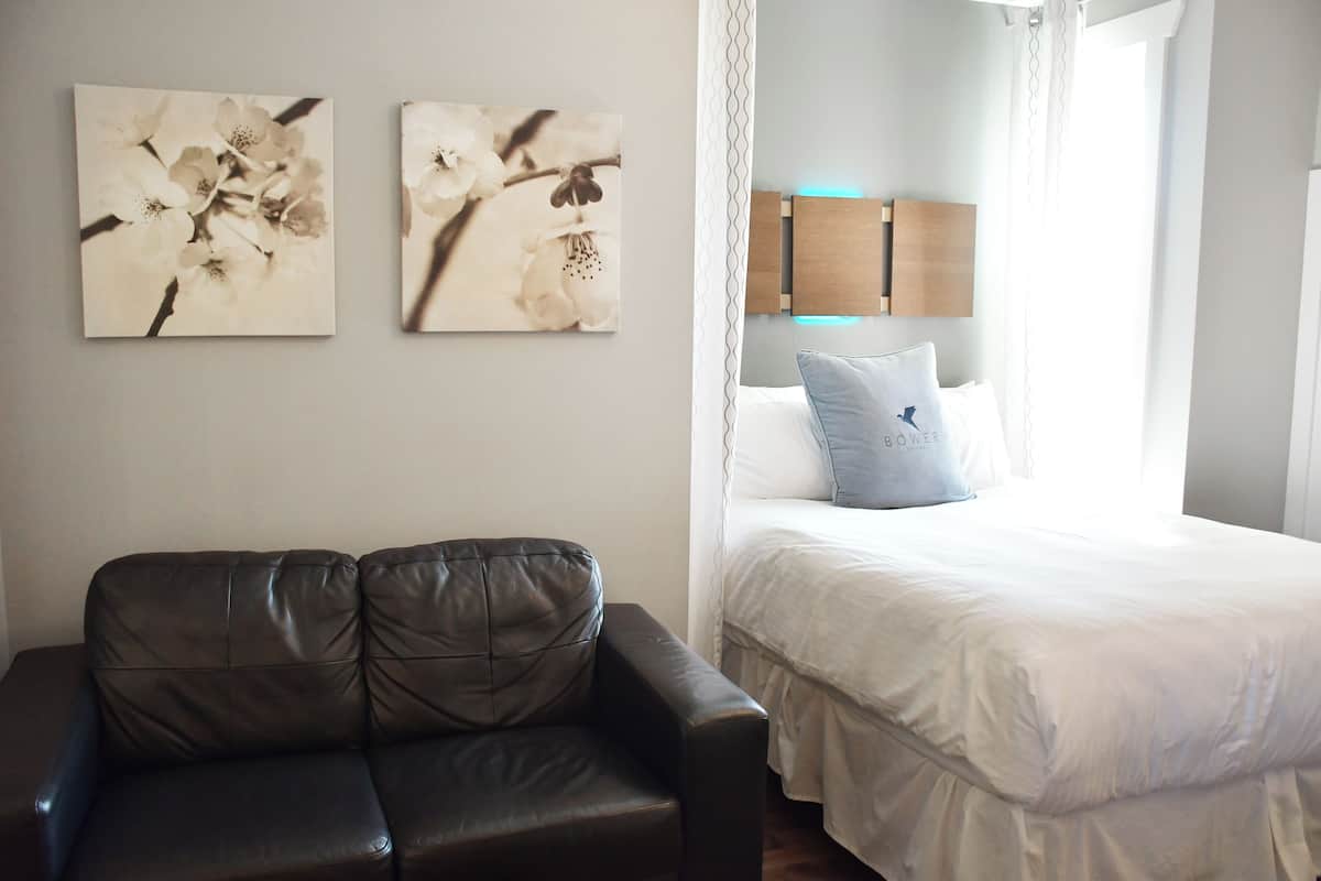 Een slaapkamer met een bed, een hoofdbord, een nachtkastje en twee aan de muur bevestigde schilderijen.