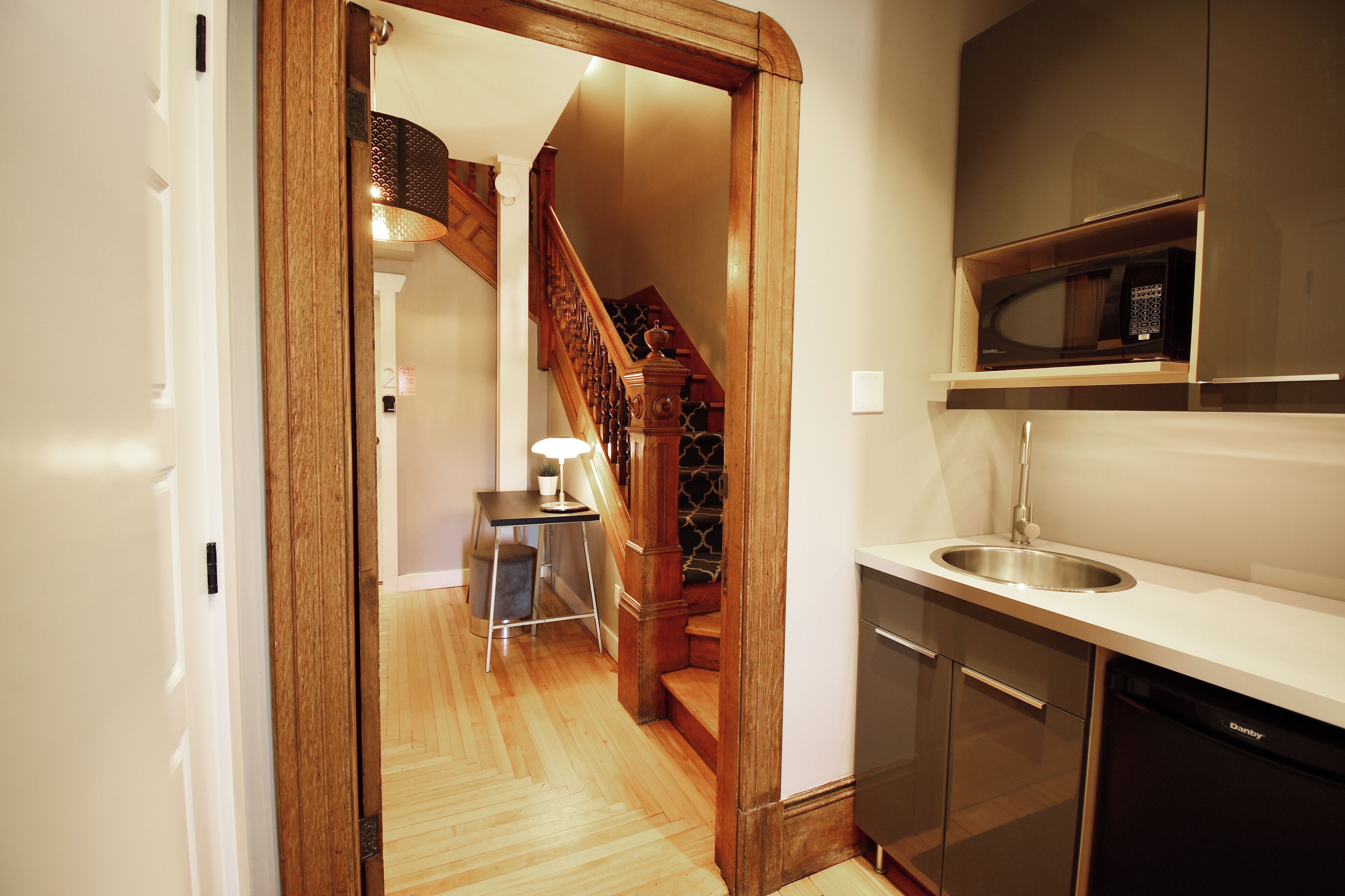 A kitchen with wooden flooring, a stainless steel sink, and a built-in microwave.