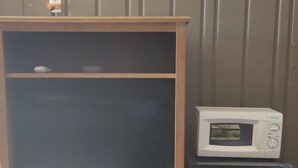 Puisesta valmistettu kaappi, jossa on laatikoita, mikroaaltouuni ja jääkaappi.