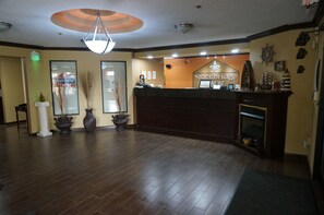 A reception area with a wooden floor, a chandelier, a fireplace, and a sign reading "Stockbridge Inn".