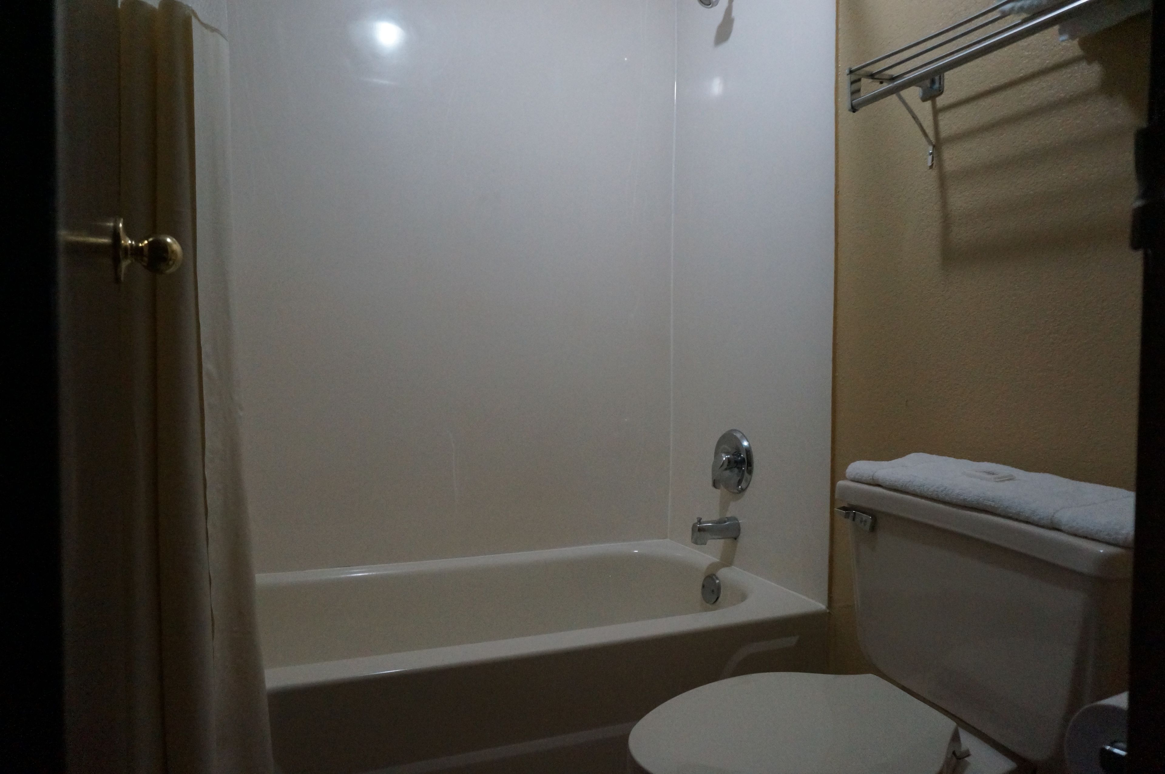 A bathroom with a bathtub, toilet, and a towel rack.