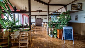 Un restaurante con suelo de madera, mesas, sillas y plantas en macetas.
