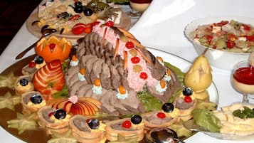 A large, ornate meat centerpiece with various garnishes and side dishes on a table.