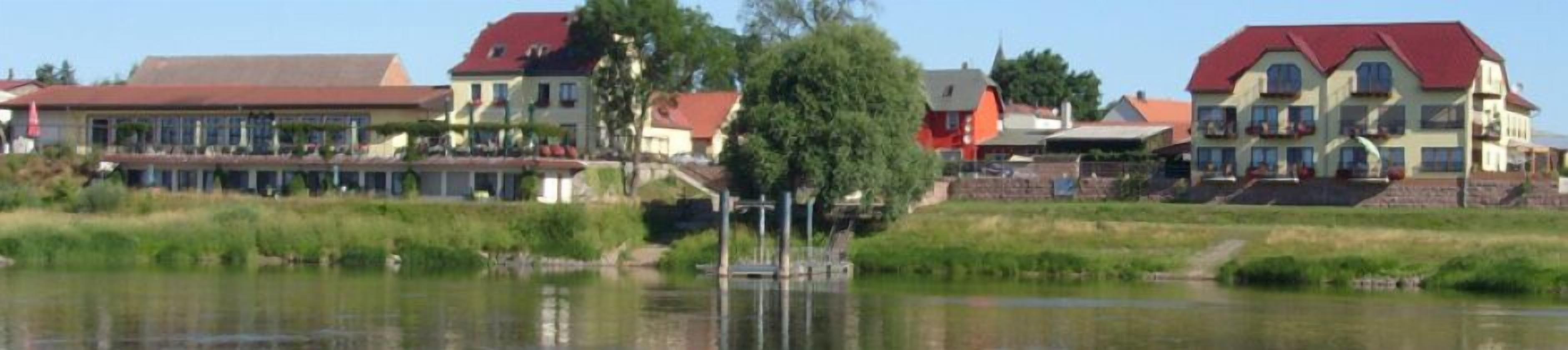 A lakeside hotel with multiple buildings, a dock, and a small boat.