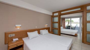 Une chambre d’hôtel avec un grand lit, une table de chevet avec un téléphone et une porte coulissante donnant sur un balcon.