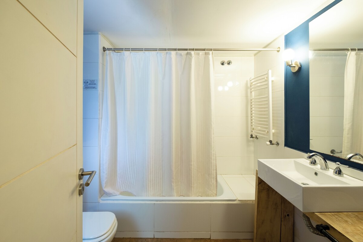 A bathroom with a bathtub, a toilet, a sink with a mirror, and a shower curtain.