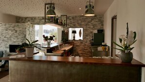 A modern kitchen with a wooden counter, stone backsplash, and pendant lighting.