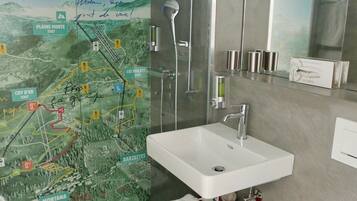A modern bathroom with a glass shower enclosure, a white sink, and a red vanity.