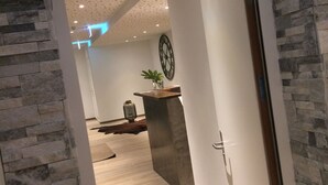 A modern interior with a stone wall, a wooden door, and a tiled floor.
