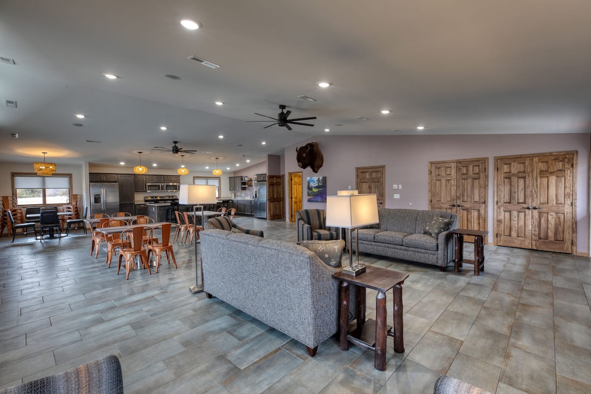 A spacious living area with a dining set, sofas, and a kitchen in the background.