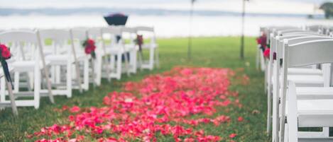 Filas de sillas blancas con pétalos de flores rojas en el suelo, sugiriendo un ambiente de ceremonia nupcial.
