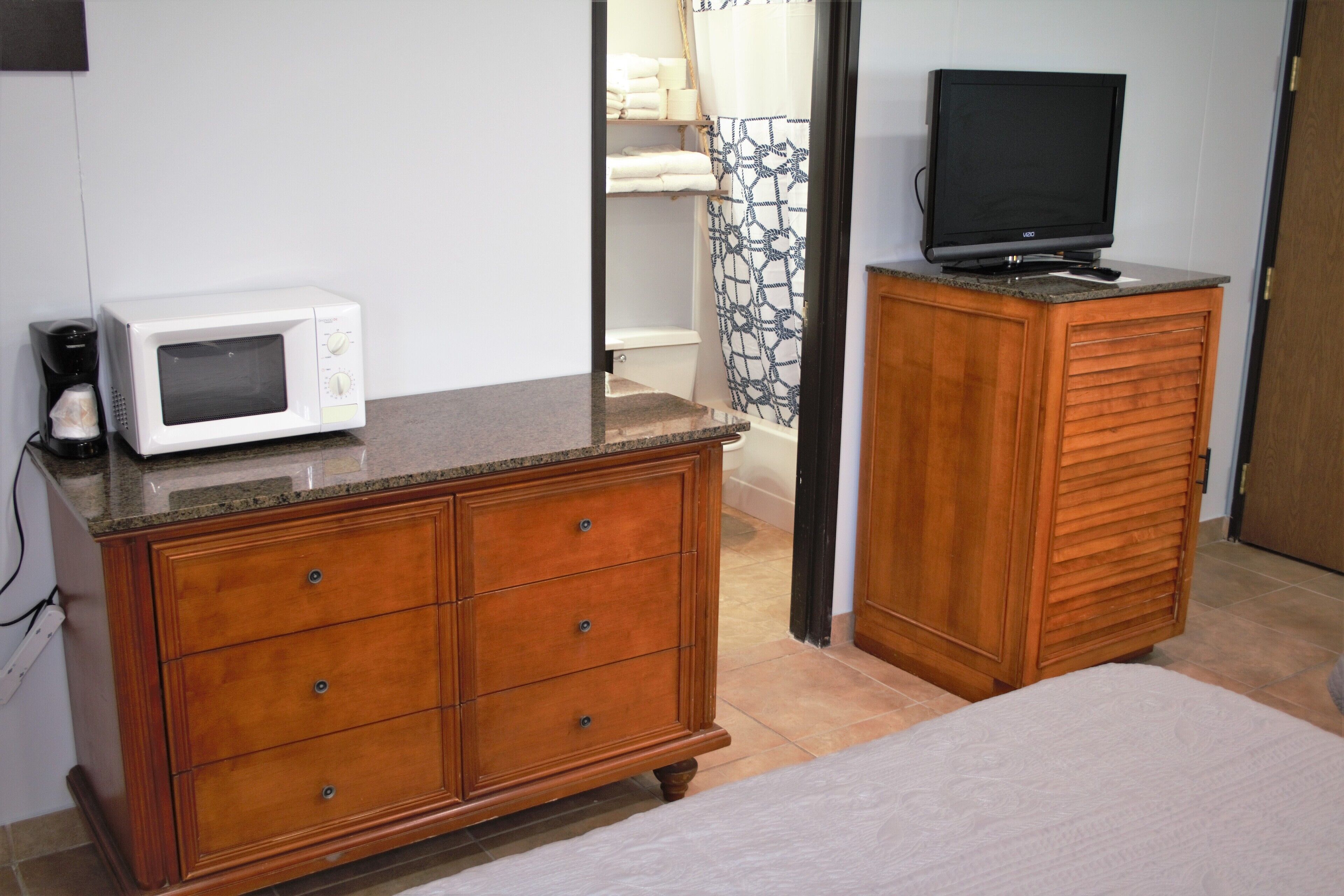 Un dormitorio con un aparador de madera, un microondas y un televisor sobre un mueble de madera.