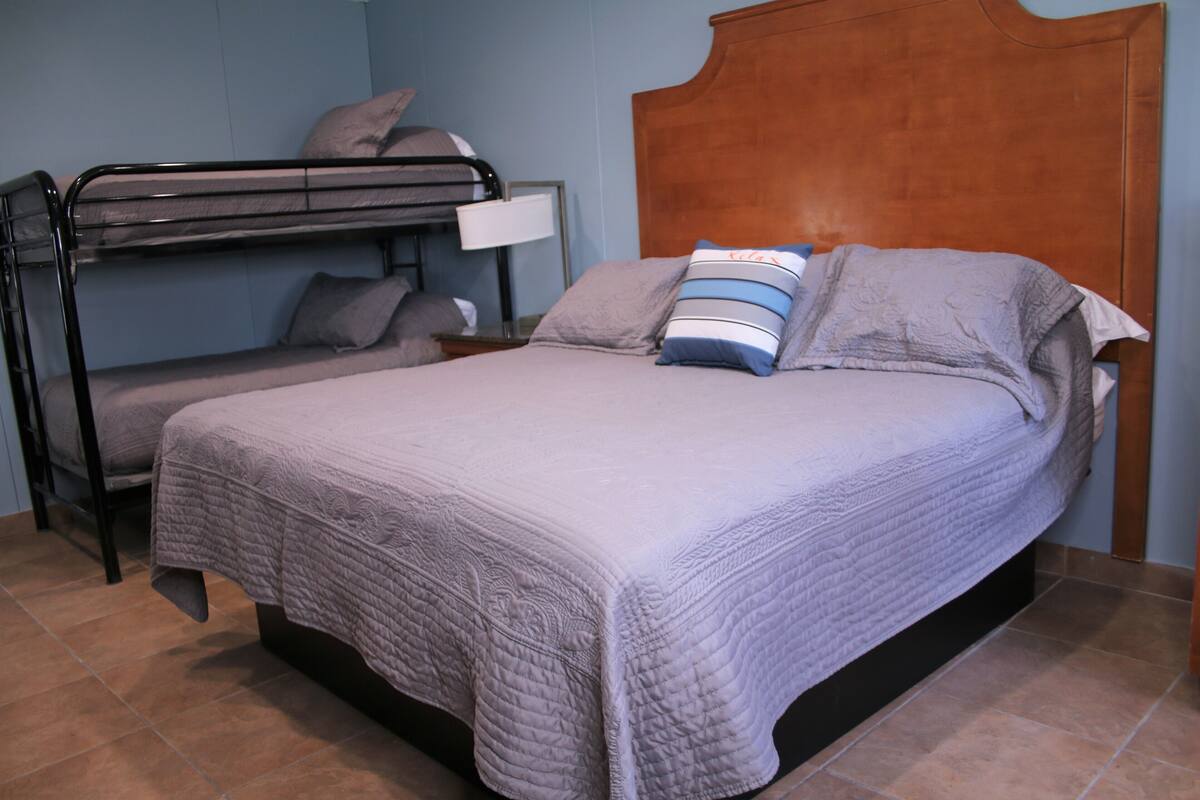 A bedroom with a bunk bed, a single bed, and a wooden headboard.