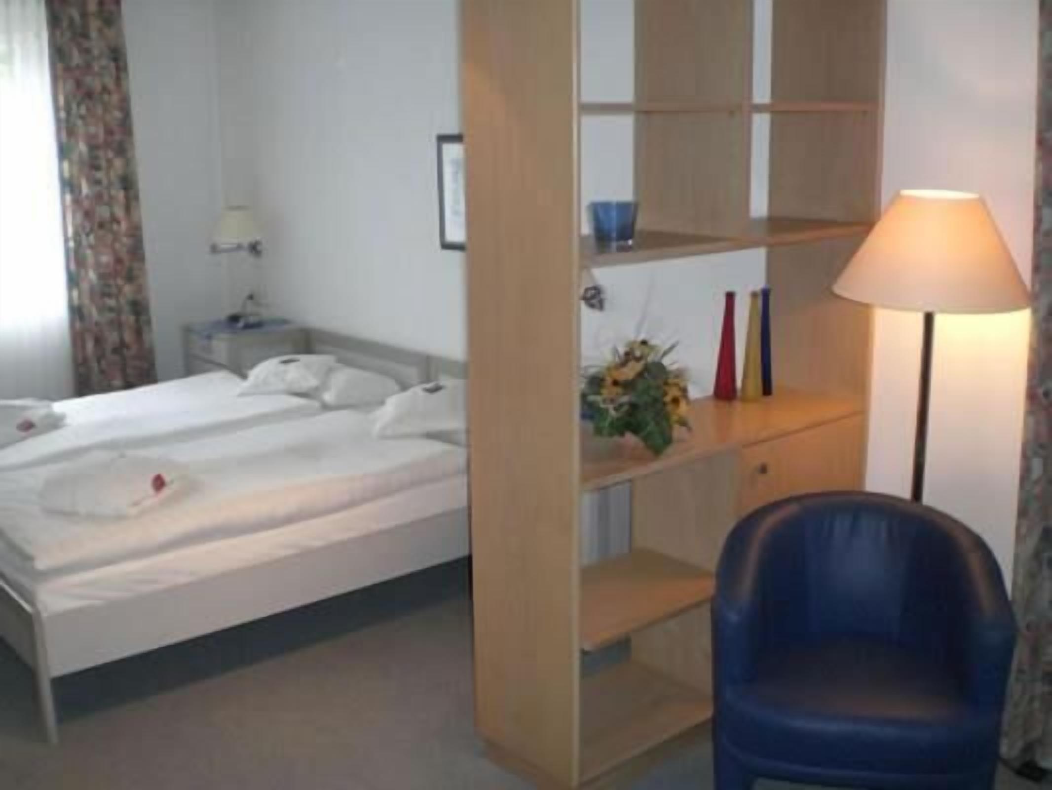 Ein Hotelzimmer mit Bett, Schreibtisch, Stuhl und Lampe.