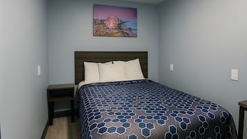Un dormitorio con cama, mesita de noche, cabecera y un cuadro colgado en la pared.