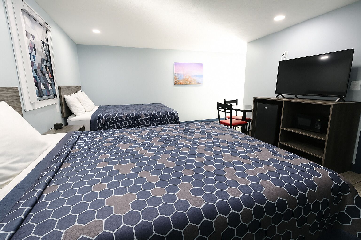 A hotel room with two beds, a TV, a desk, and a chair.