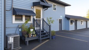 A two-story motel with a blue exterior, a front porch with potted plants, and a parking lot. - Hillsboro Inn & Suites (Hillsboro)
