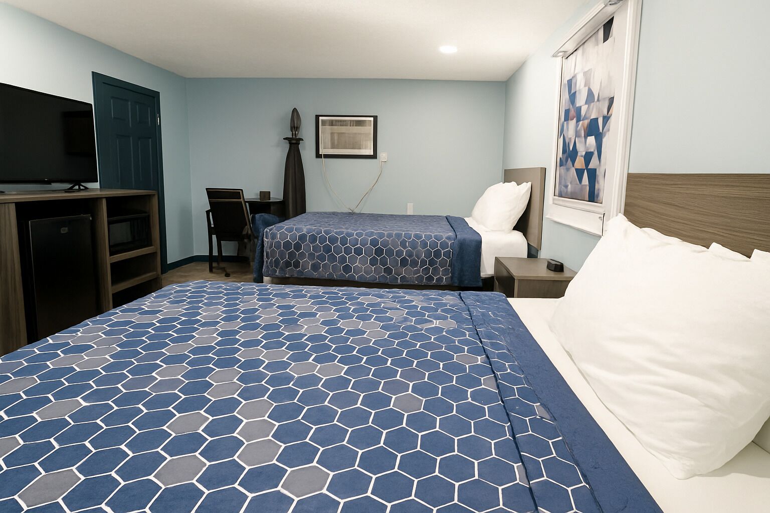 Una habitación de hotel con una cama grande, un escritorio, una silla, un televisor y una puerta.