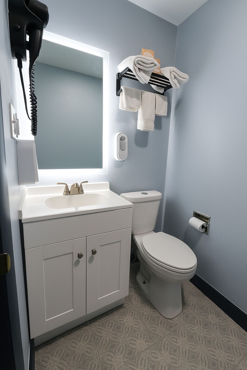 Un baño con tocador blanco, inodoro y perchero.