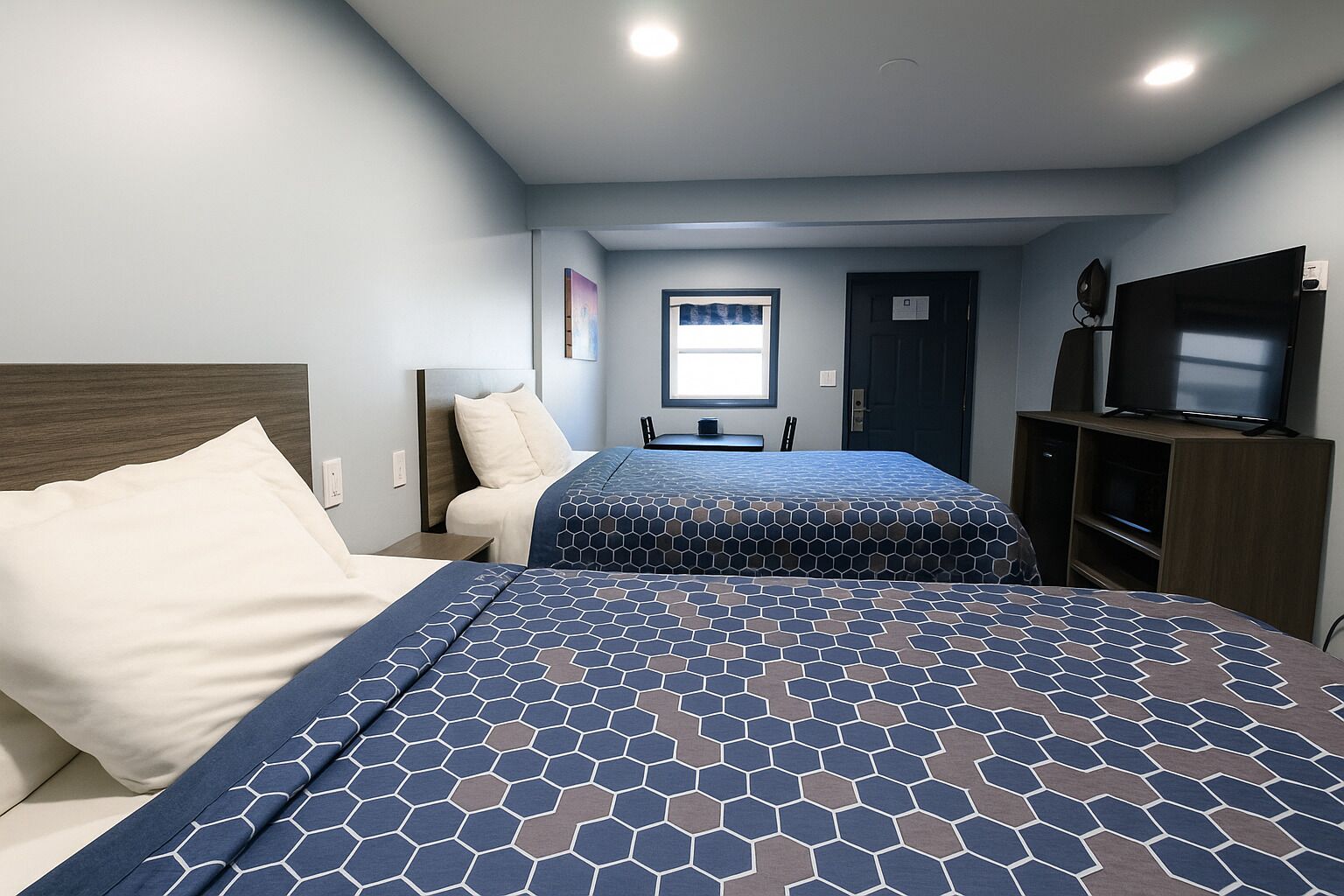 A hotel room with two beds, a television, and a window with curtains.