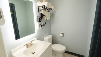 A bathroom with a white sink, a toilet, a towel rack, and a mirror.