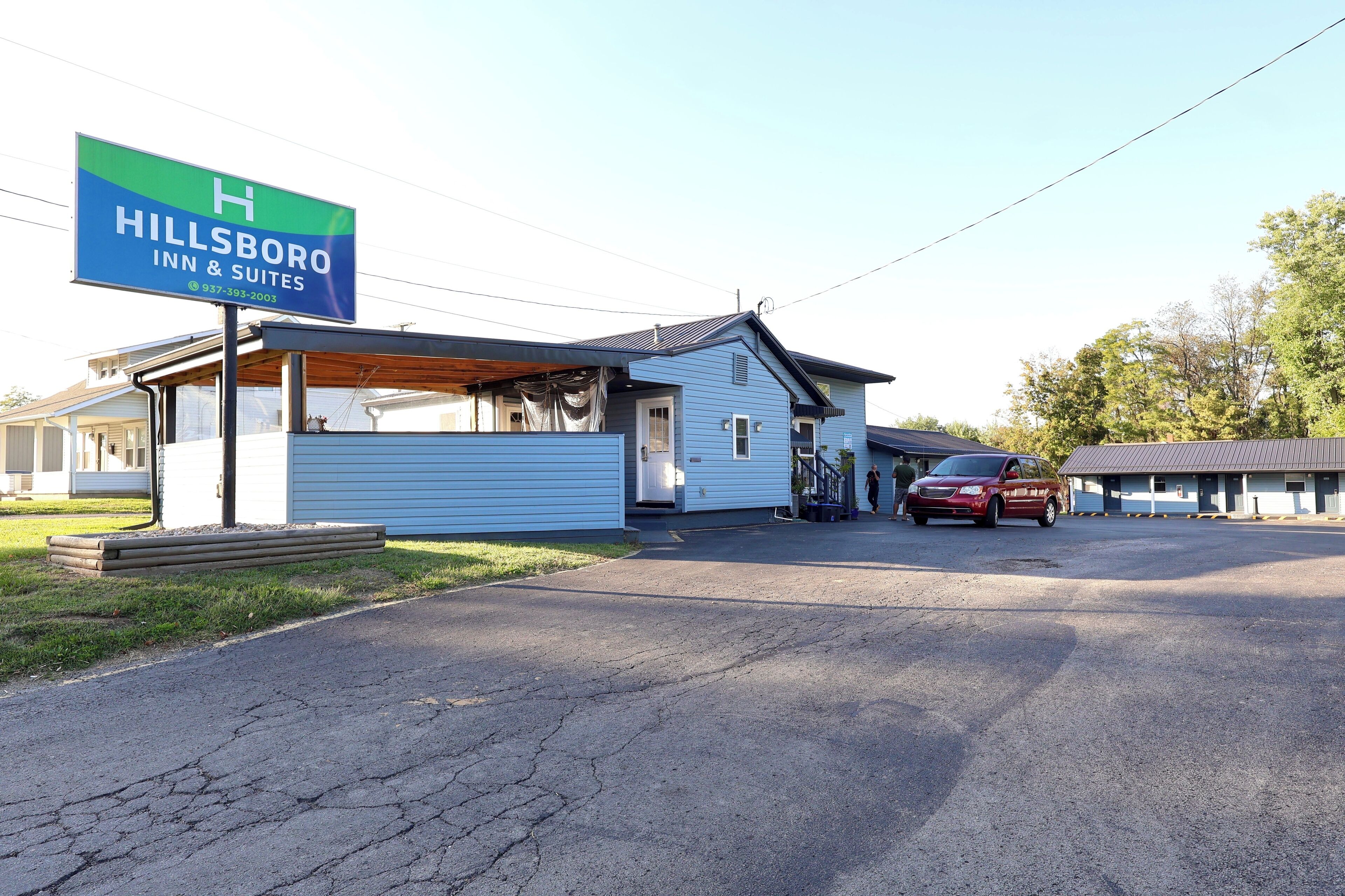 Hillsboro Inn & Suites mit überdachter Außenbereich, einem roten Auto vor der Fassade und wolkenlosem Himmel.