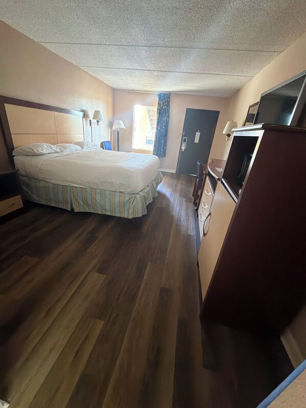 Une chambre d’hôtel avec un lit, un bureau, une télévision et une porte.