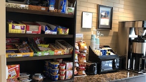 Um quiosque de autoatendimento com diversas opções de lanches e bebidas, incluindo cereais em embalagem, salgadinhos e máquinas de café.