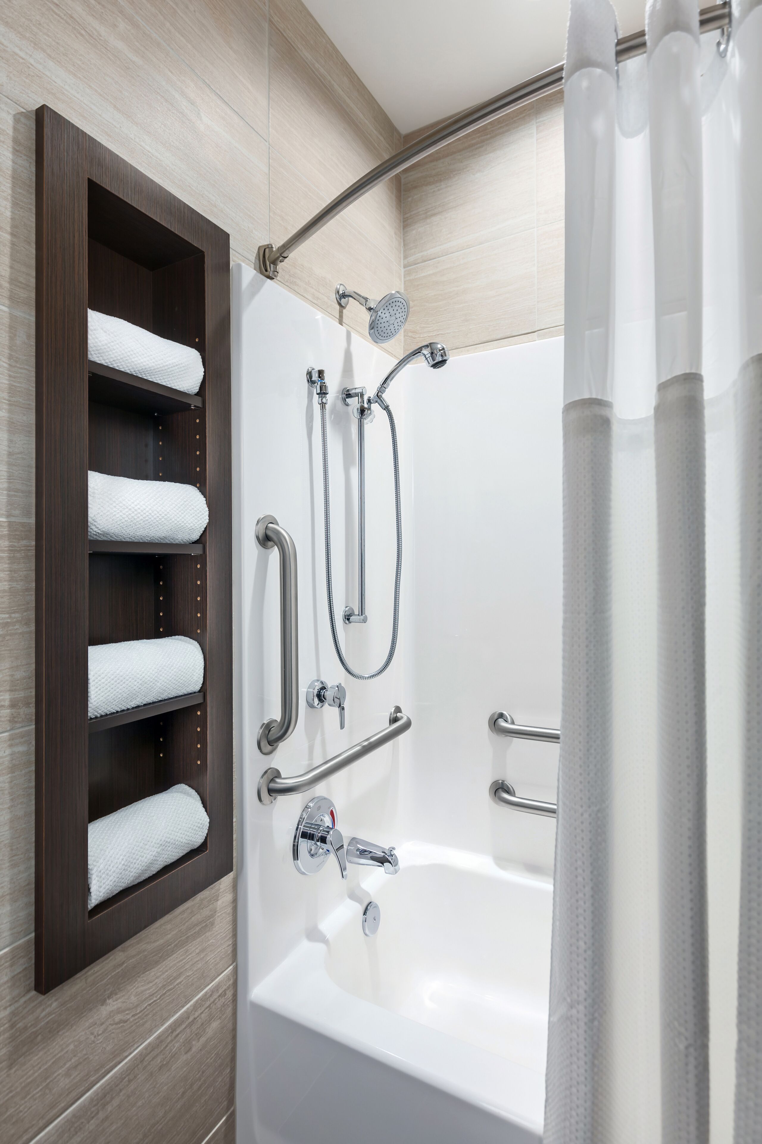 A modern bathroom with a bathtub, shower, and towel rack.