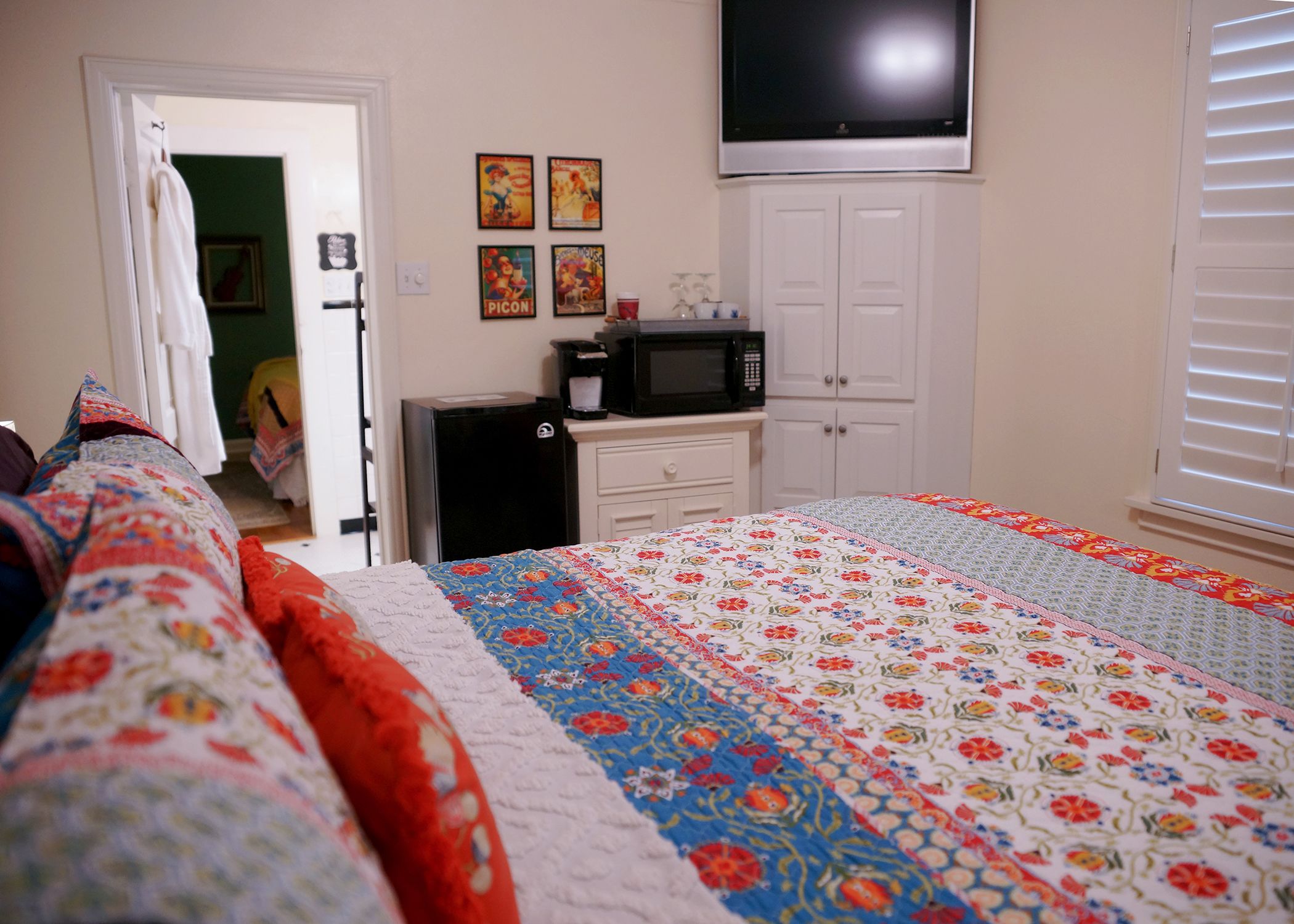 Une chambre à coucher comprenant un lit, une télévision, un four à micro-ondes et une armoire.