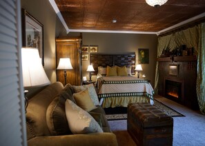 A cozy room with a bed, a wooden chest, and a fireplace. - Fiddler's Inn (Carlsbad)