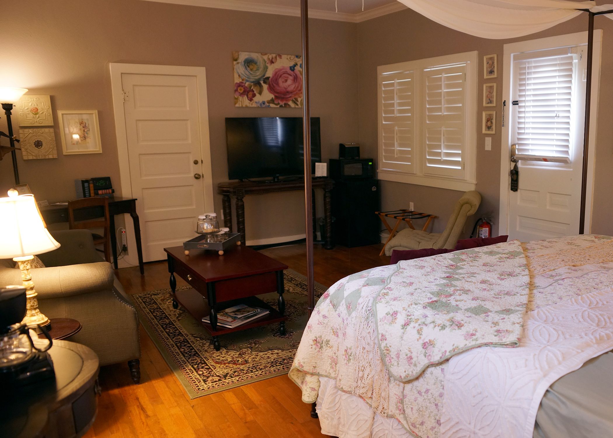 A cozy bedroom with a bed, a television, a desk, and a chair.