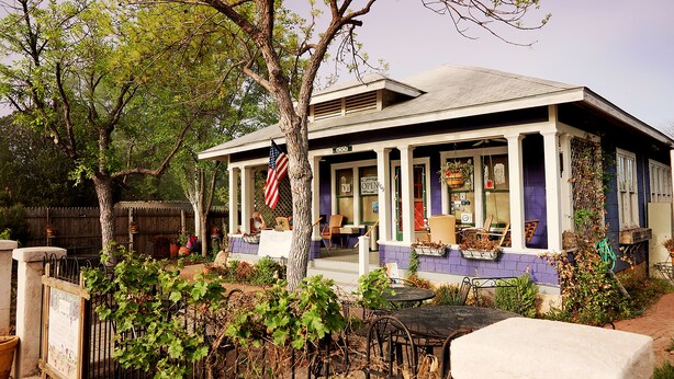A two-story building with a porch, outdoor seating, and a flag. - Fiddler's Inn (Carlsbad)