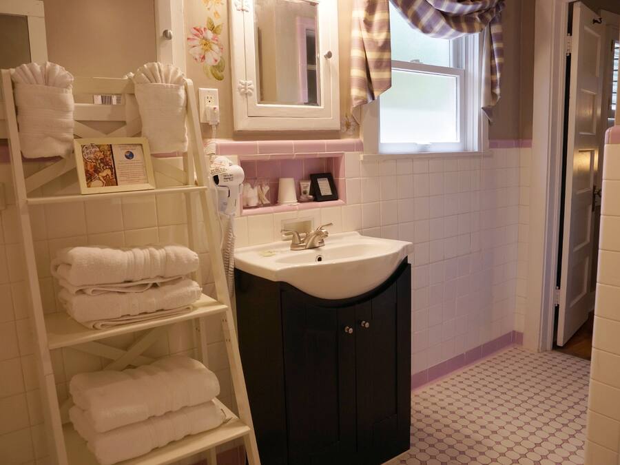 A bathroom with a white sink, dark cabinets, and a towel rack with folded towels.