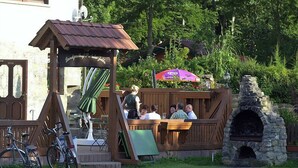 An outdoor seating area with wooden benches and a stone fireplace. - Landgasthof Probstei Zella (Amt Creuzburg)