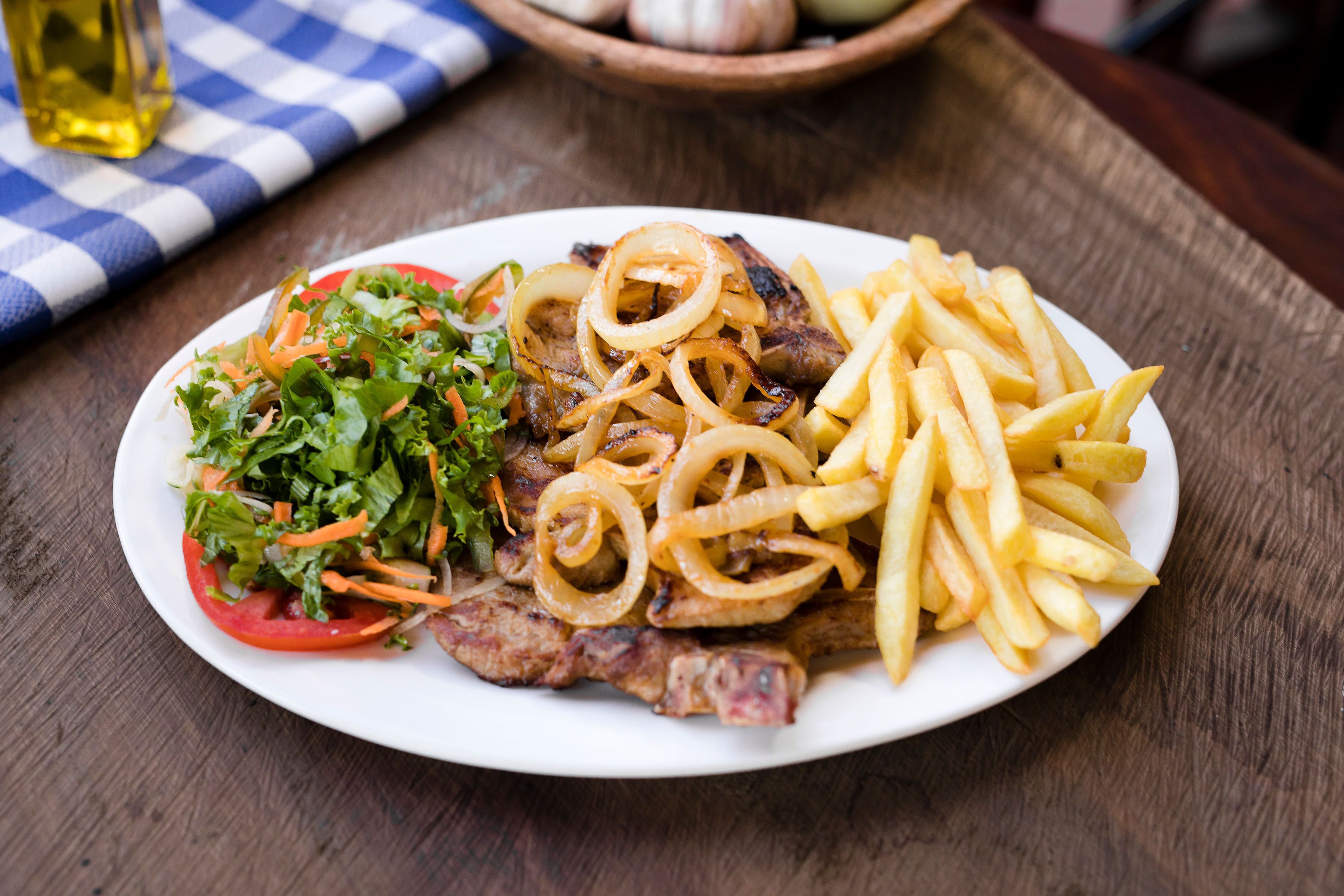 Un piatto con bistecca, patatine fritte e insalata.