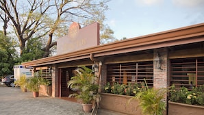 A building with a sign reading "BOPROS" and a brick facade. There are potted plants along the sidewalk. - Hotel Boyeros (Liberia)