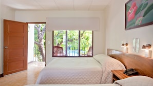 A hotel room with two beds, a wooden headboard, a nightstand, a telephone, and a view of a balcony with a tree and a pool. - Hotel Boyeros (Liberia)