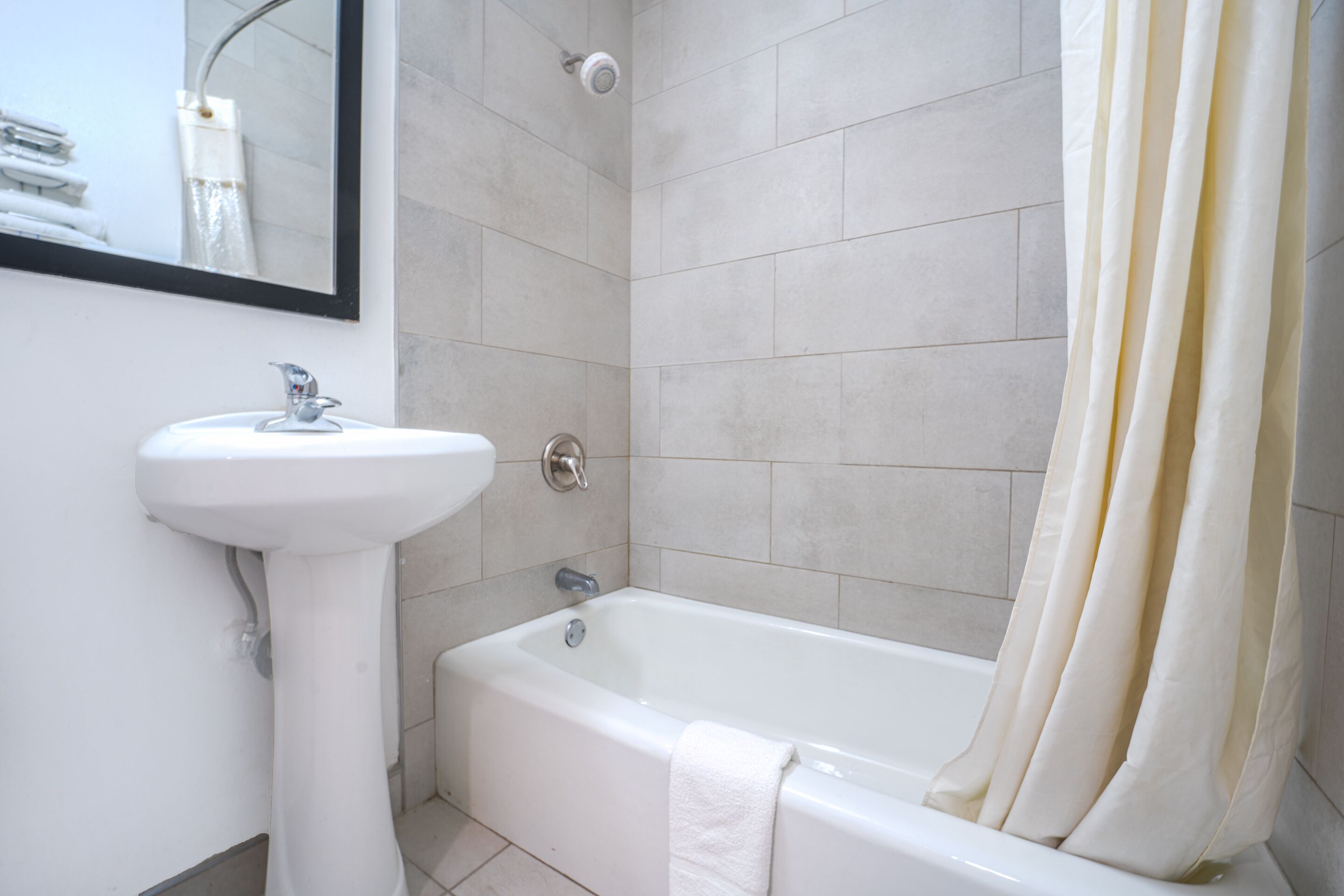 A bathroom with a white sink, a bathtub, and a shower curtain.