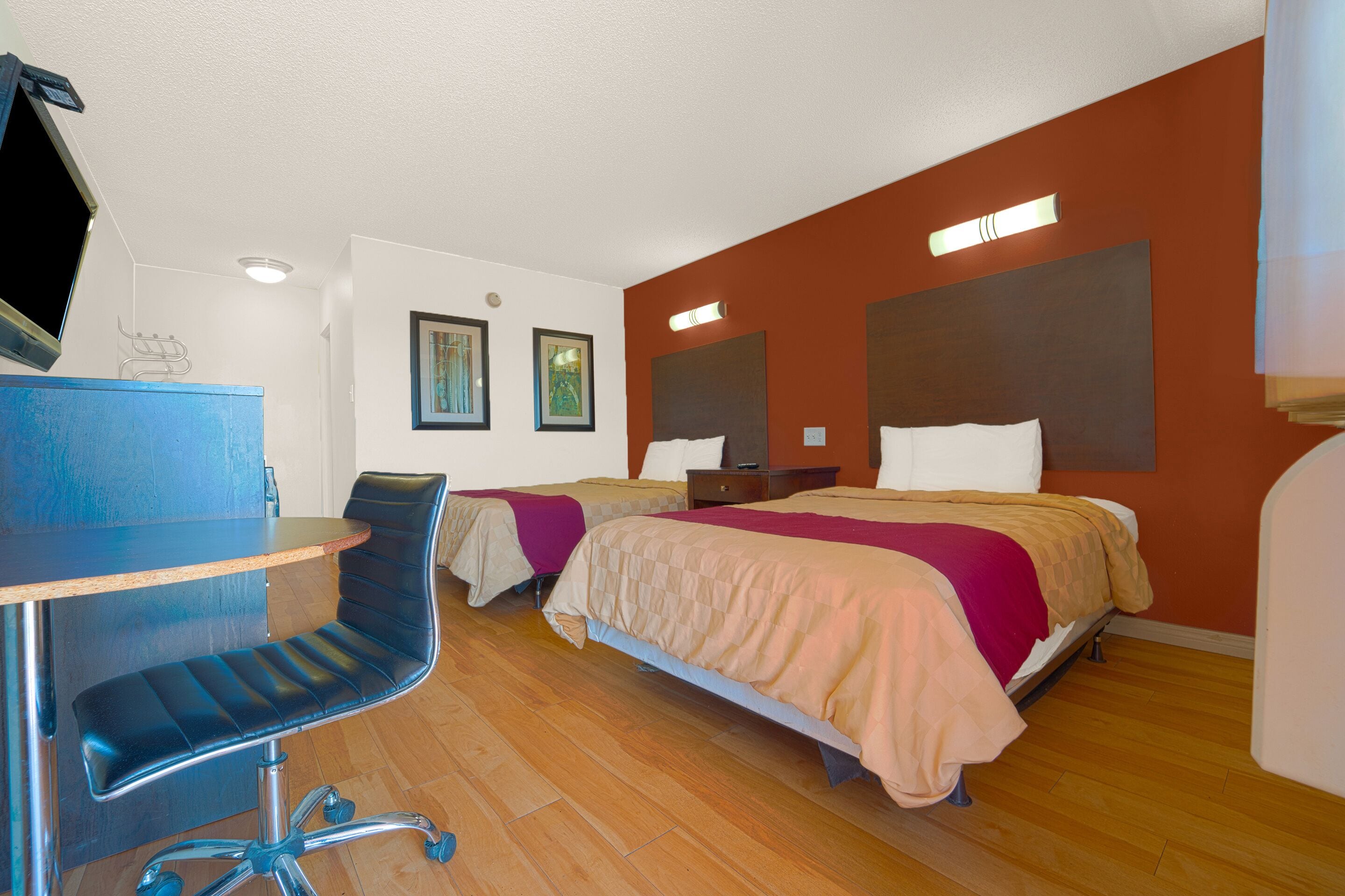 A hotel room with two beds, a desk, and a chair.