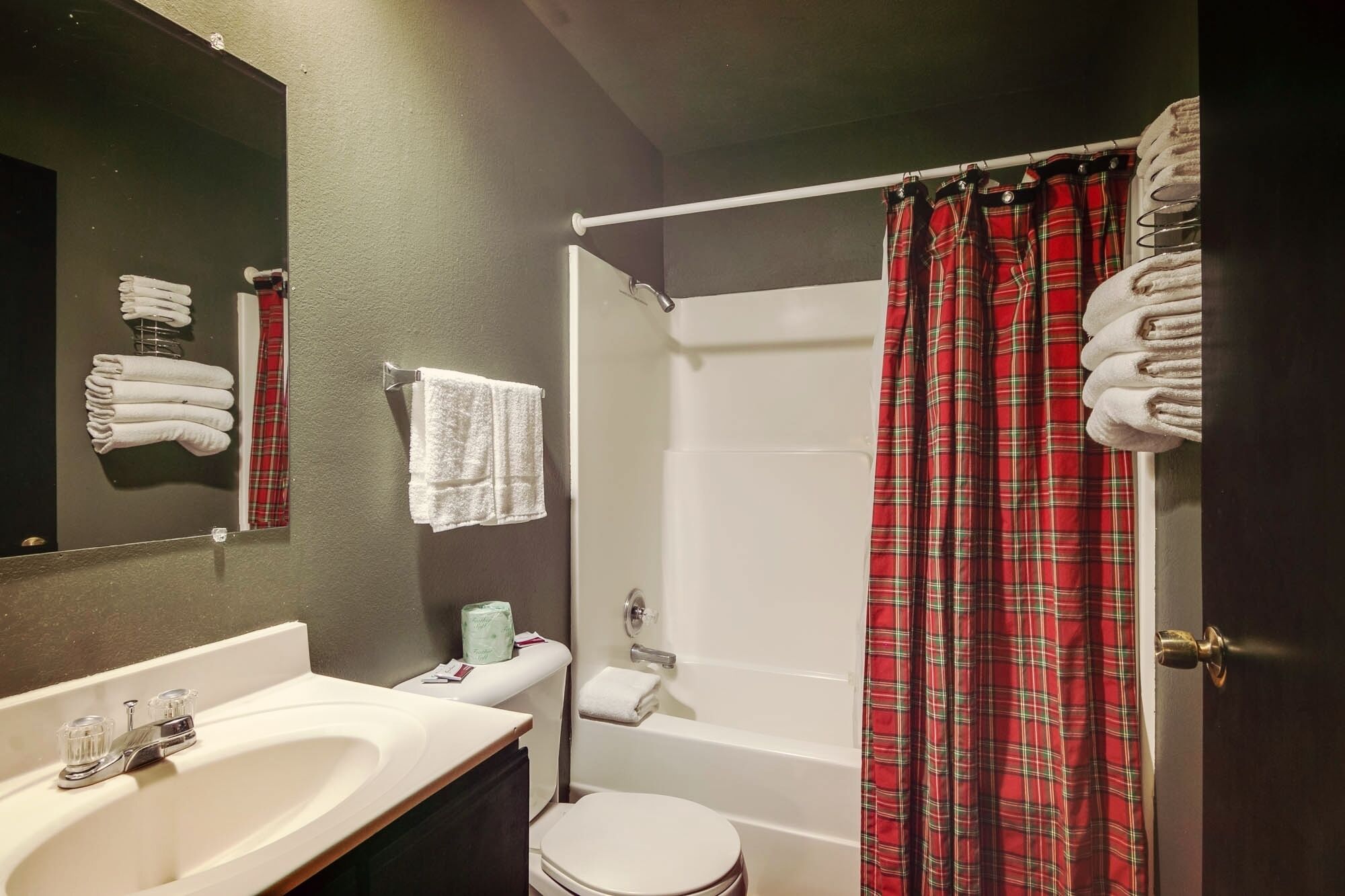 Un bagno con un lavandino bianco, un water, una tenda per la doccia e asciugamani appesi al muro.