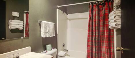Un bagno con un lavandino bianco, un water, una tenda per la doccia e asciugamani appesi al muro.